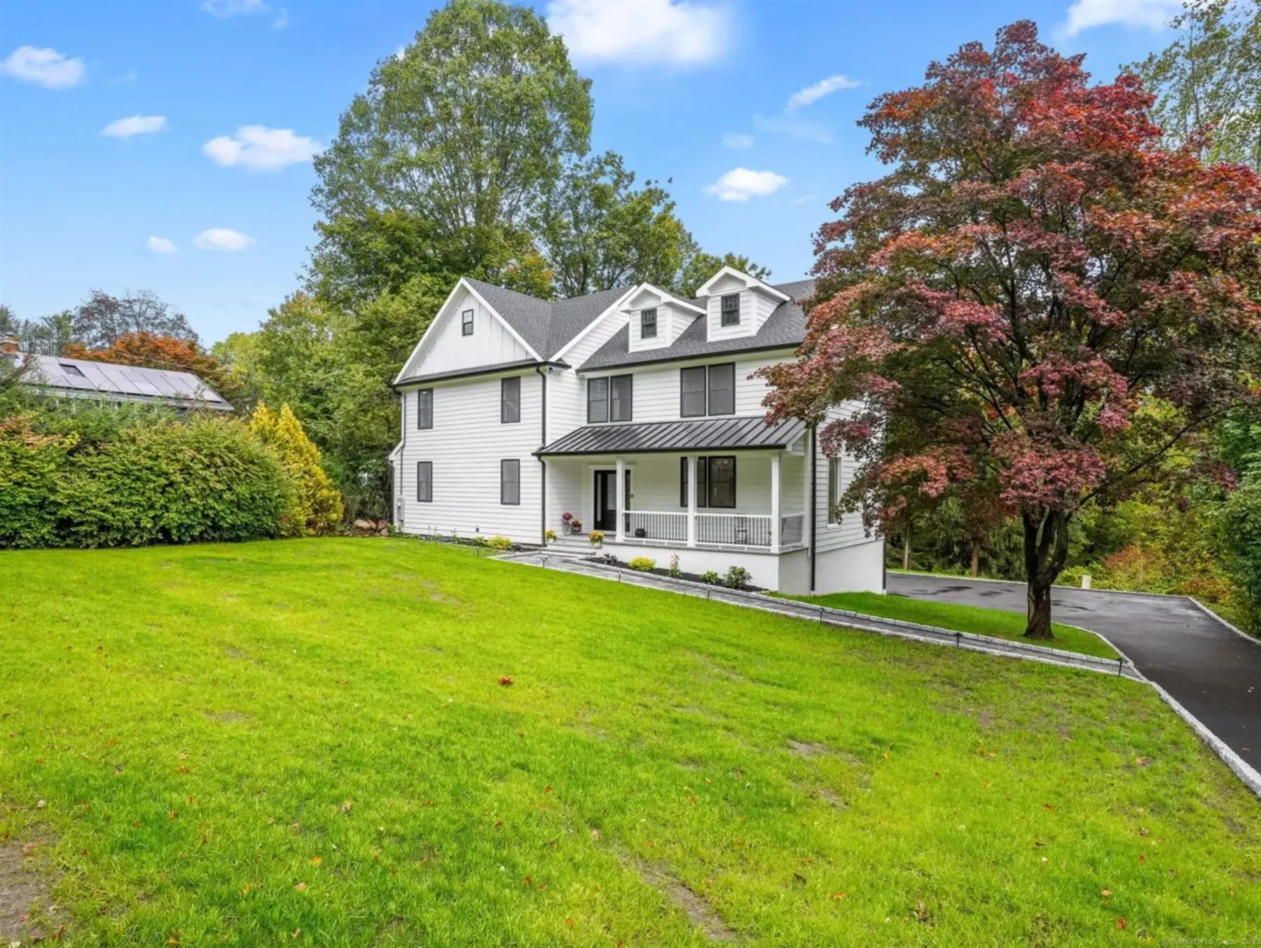 White home with front porch among autumn trees
