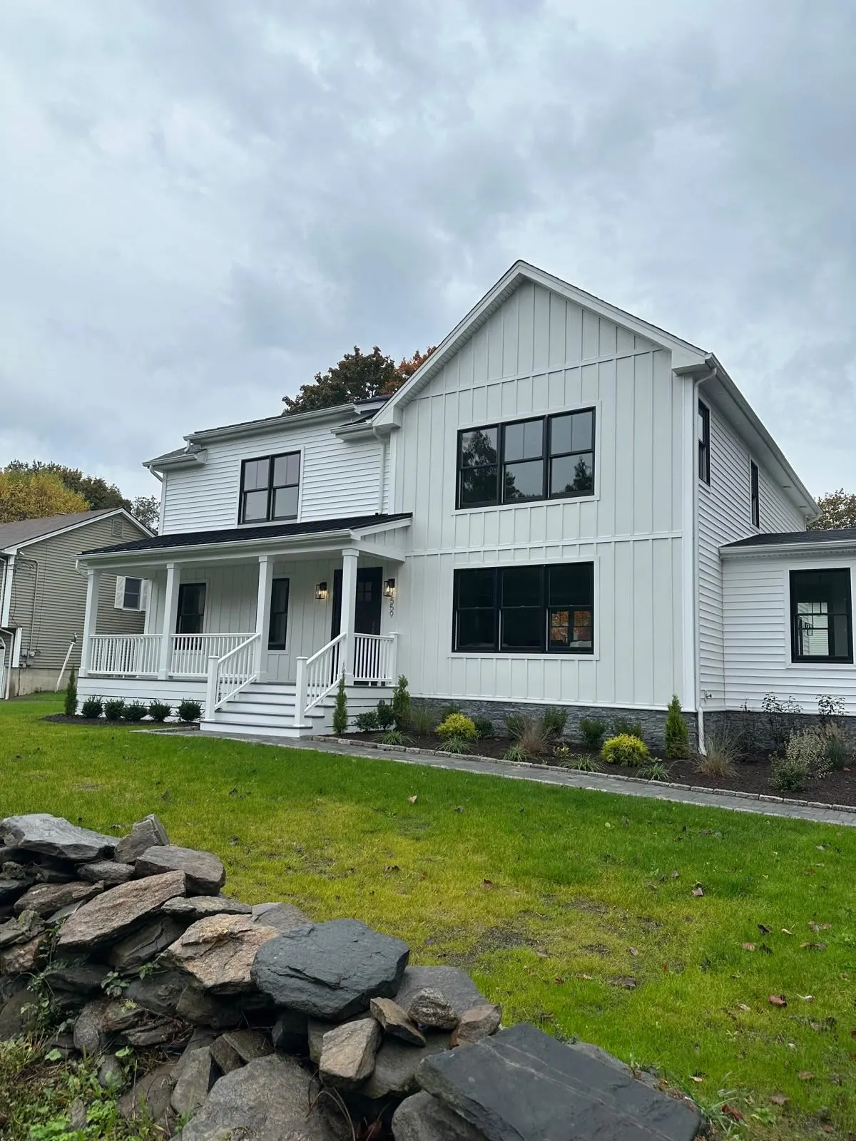 Finished white farmhouse with black windows and front porch