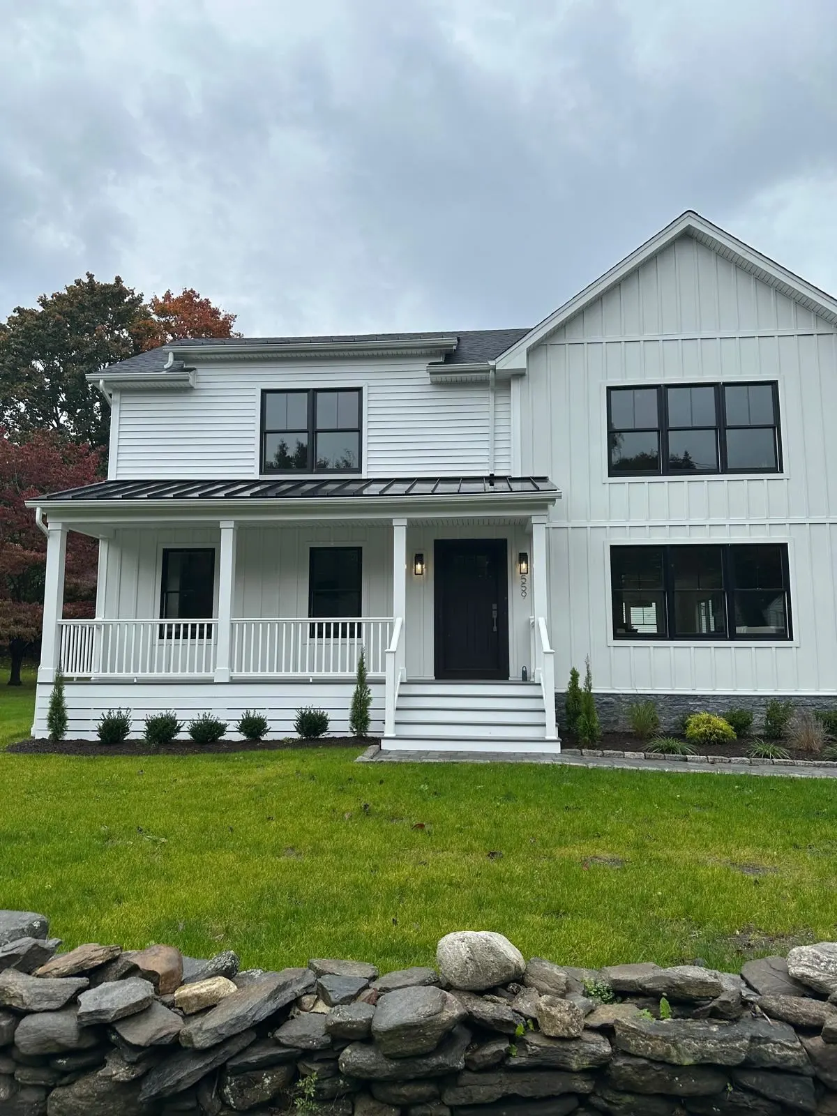 Finished farmhouse with covered front porch and stone wall